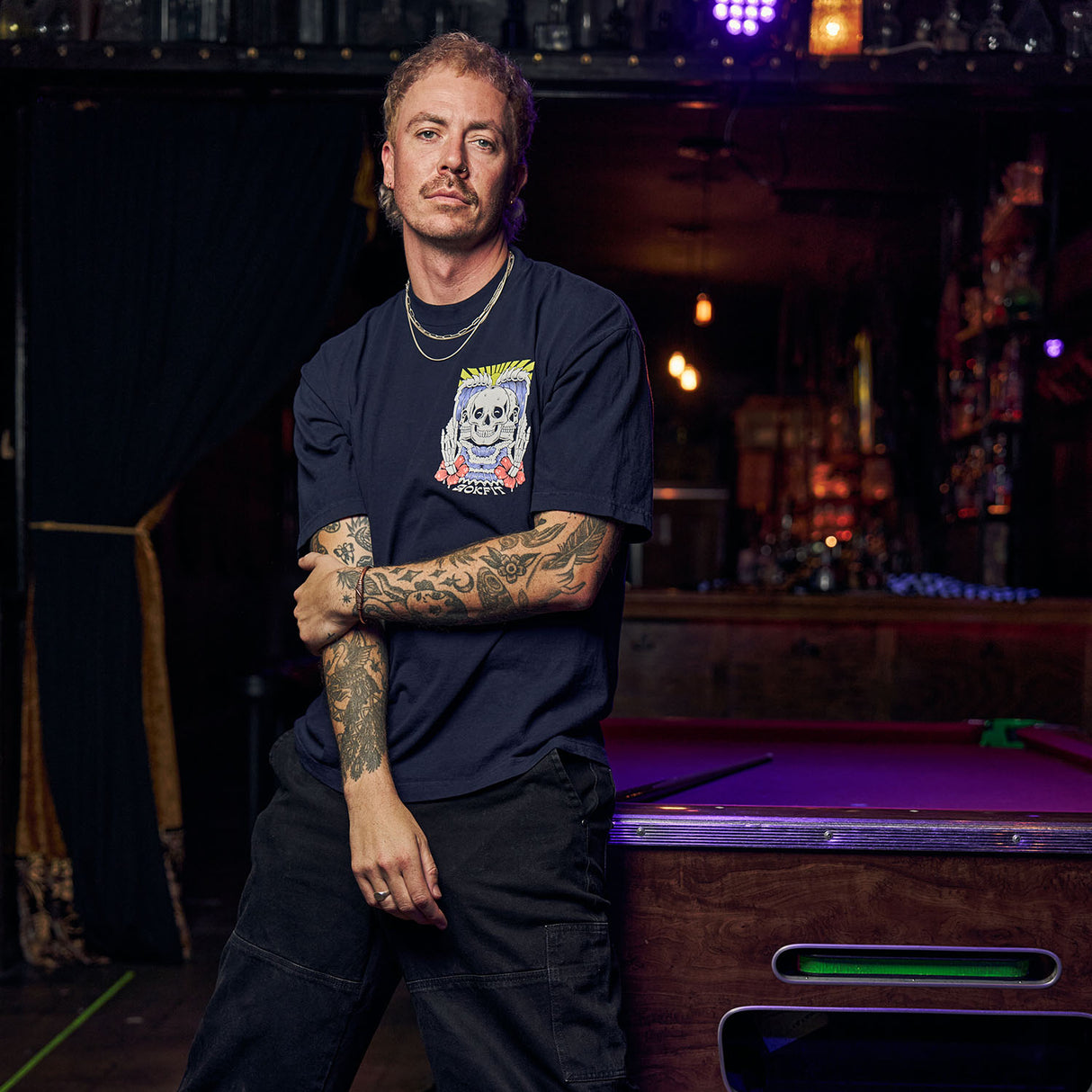 Male model in bar wearing navy blue Street Tee with 'Discipline Weighs Ounces, Regrets Weighs Tons' graphic