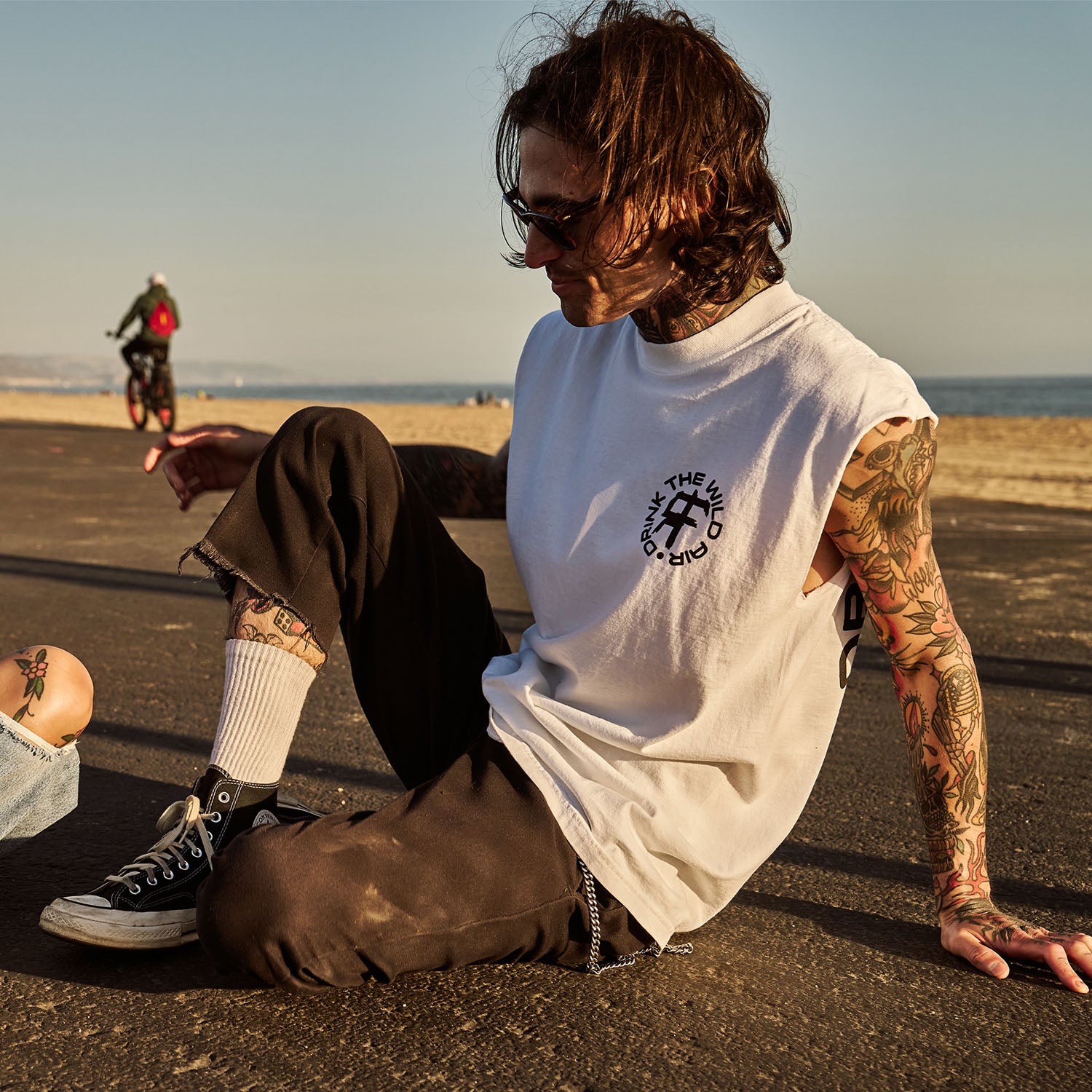 Male model outdoors wearing a sleeveless street tee with 'Drink The Wild Air' graphic