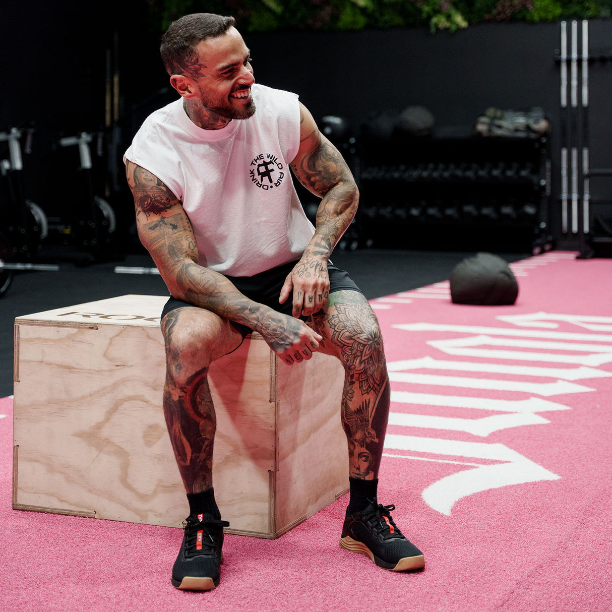 Male model in gym wearing a sleeveless street tee with 'Drink The Wild Air' graphic