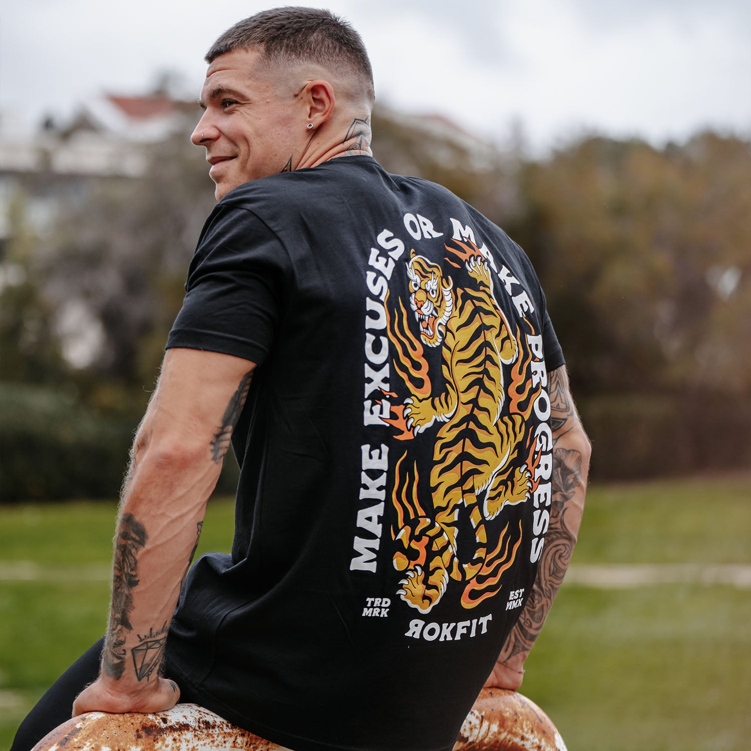 Male model outdoors wearing unisex Active Tee with 'Make Excuses or Make Progress' graphic