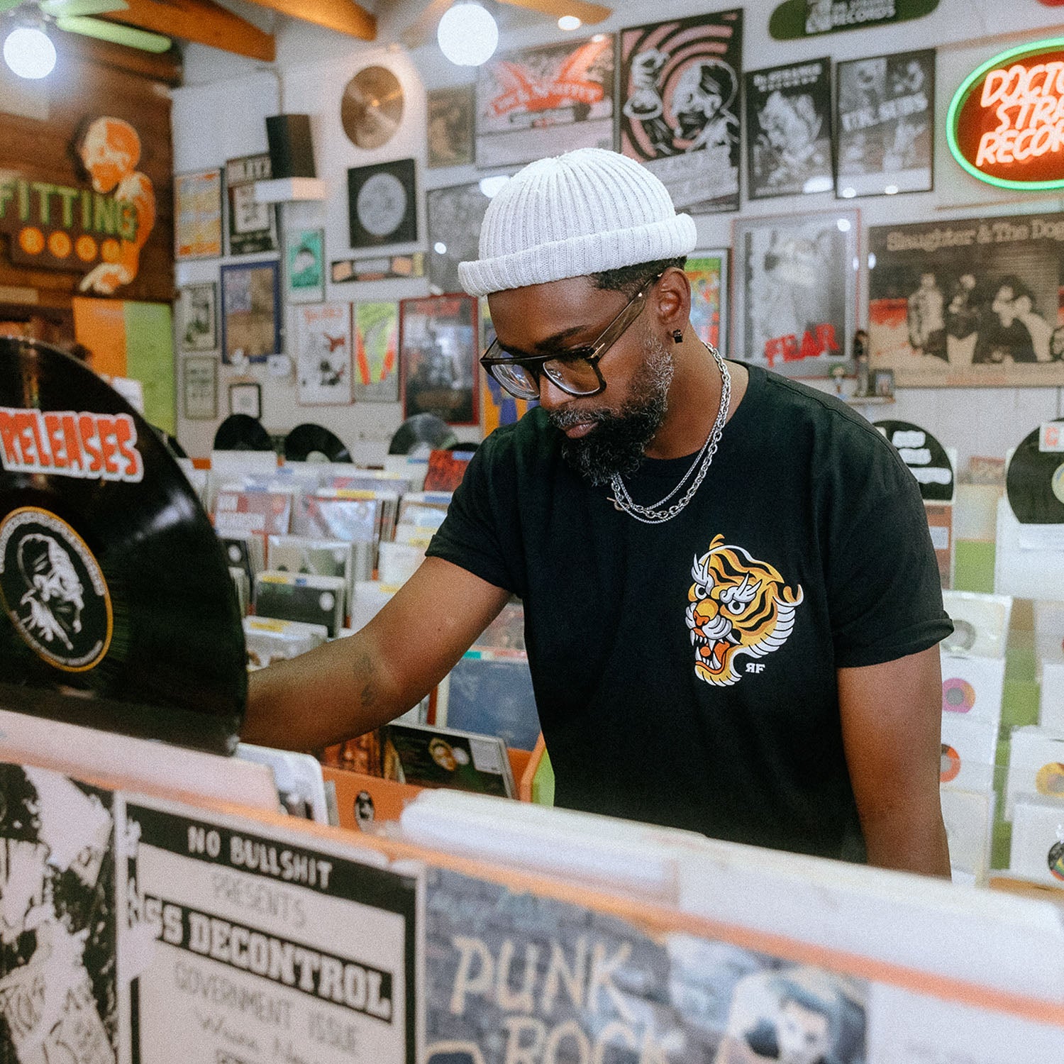 Male model in record store wearing unisex Active Tee with 'Make Excuses or Make Progress' graphic