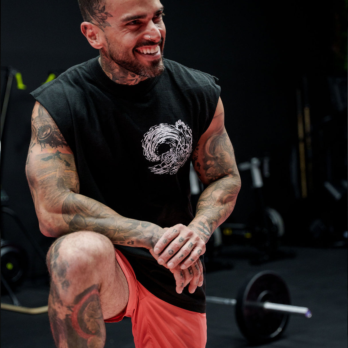 Male model in a gym wearing sleeveless Street Tee with 'Own The Grind' graphic