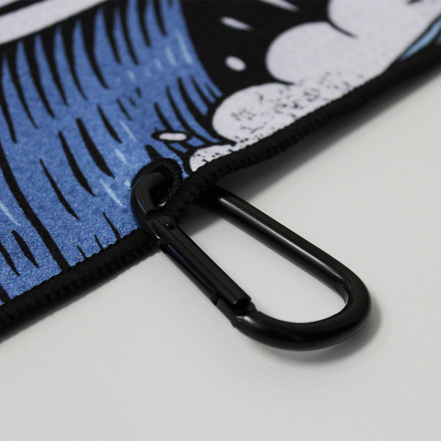 Close up of Utility Towel black carabiner clip with 'Own The Grind' graphic