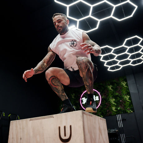 Male model box jumping in gym wearing a sleeveless street tee with 'Drink The Wild Air' graphic