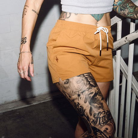 Female model on stairs wearing women's gold Hybrid Shorts