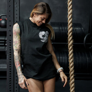 Female model in a gym wearing sleeveless Street Tee with 'Own The Grind' graphic